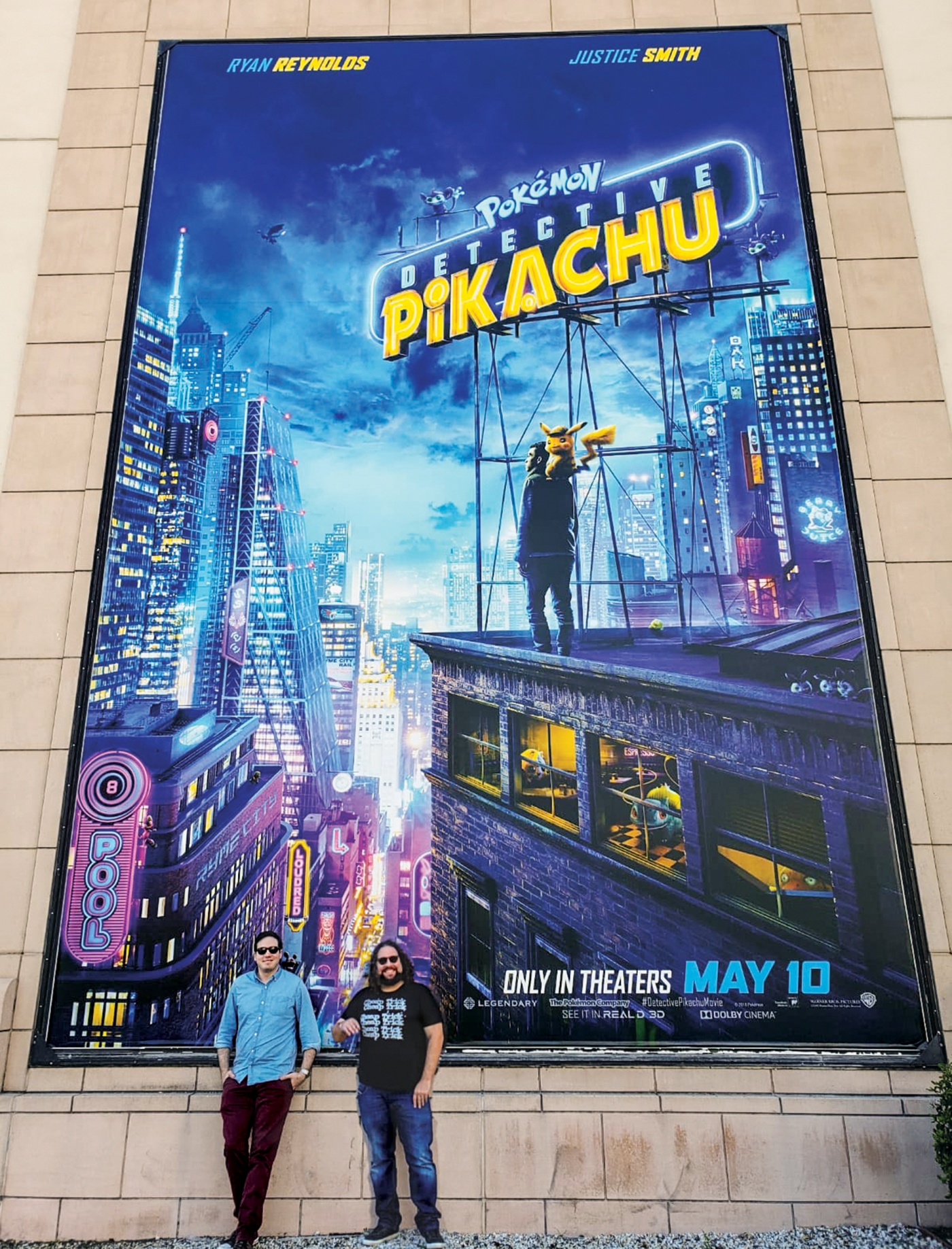 Dan Hernandez &rsquo;06 and Benji Samit &rsquo;06 standing in front of a Pok&eacute;mon: Detective Pikachu poster